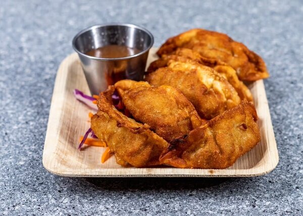 Pan-fried gyoza on a palm-leaf plate with dipping sauce