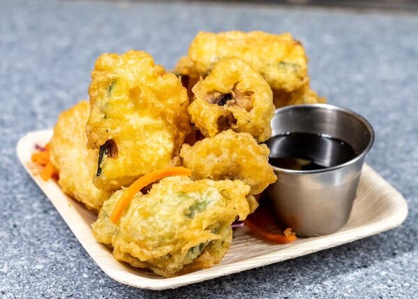 Battered vegetable tempura with a cup of dipping sauce